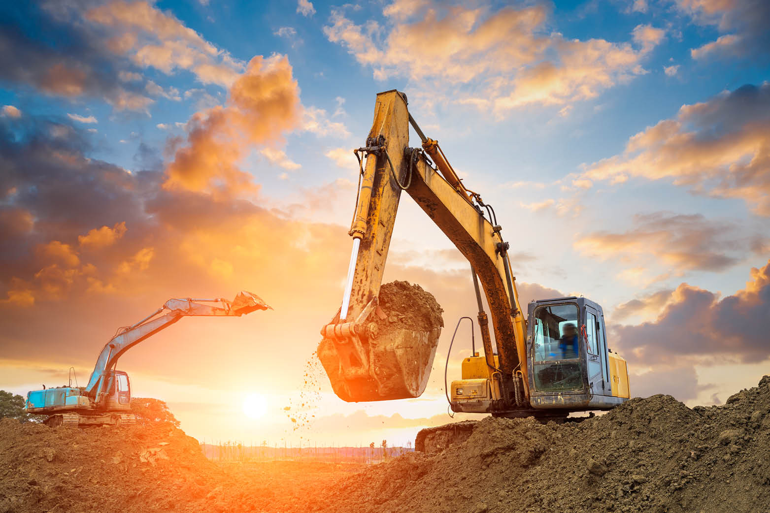 sunset pic of excavators using buckets digging trenches for property development